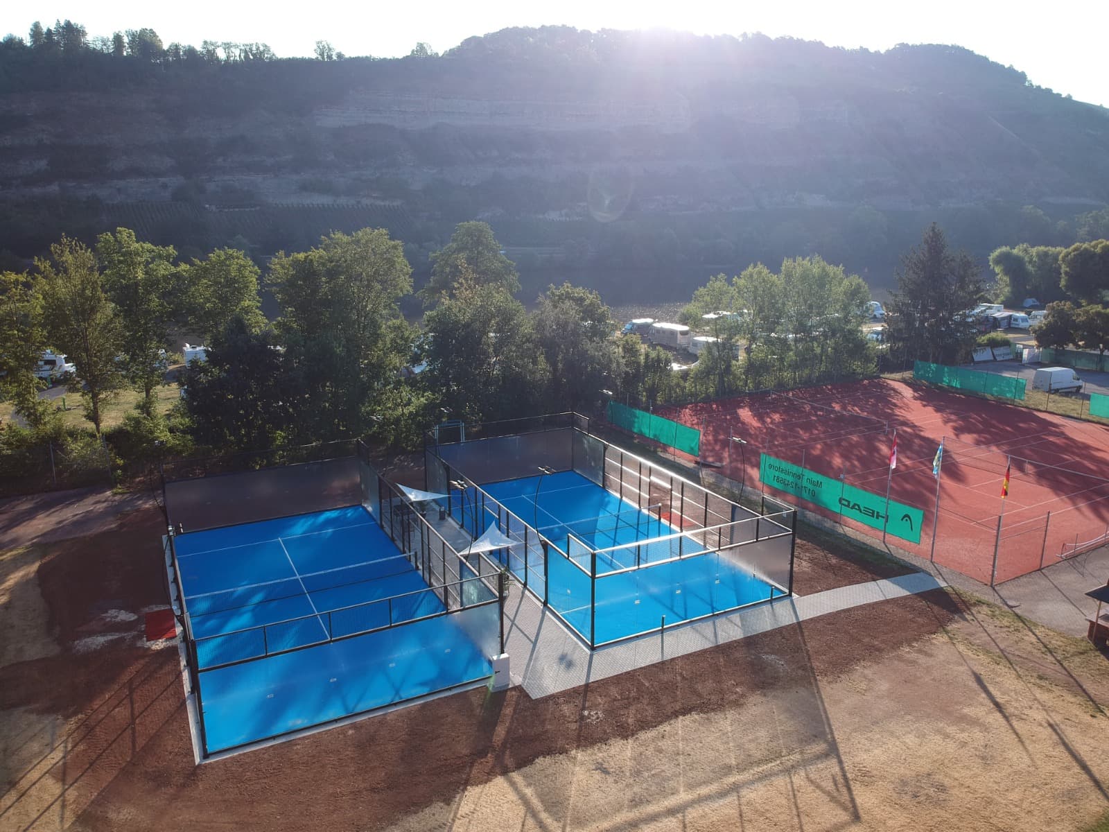 Luftaufnahme der Padelarena Zellingen mit beiden Außencourts im Morgenlicht, dahinter die Weinberge über dem Maintal