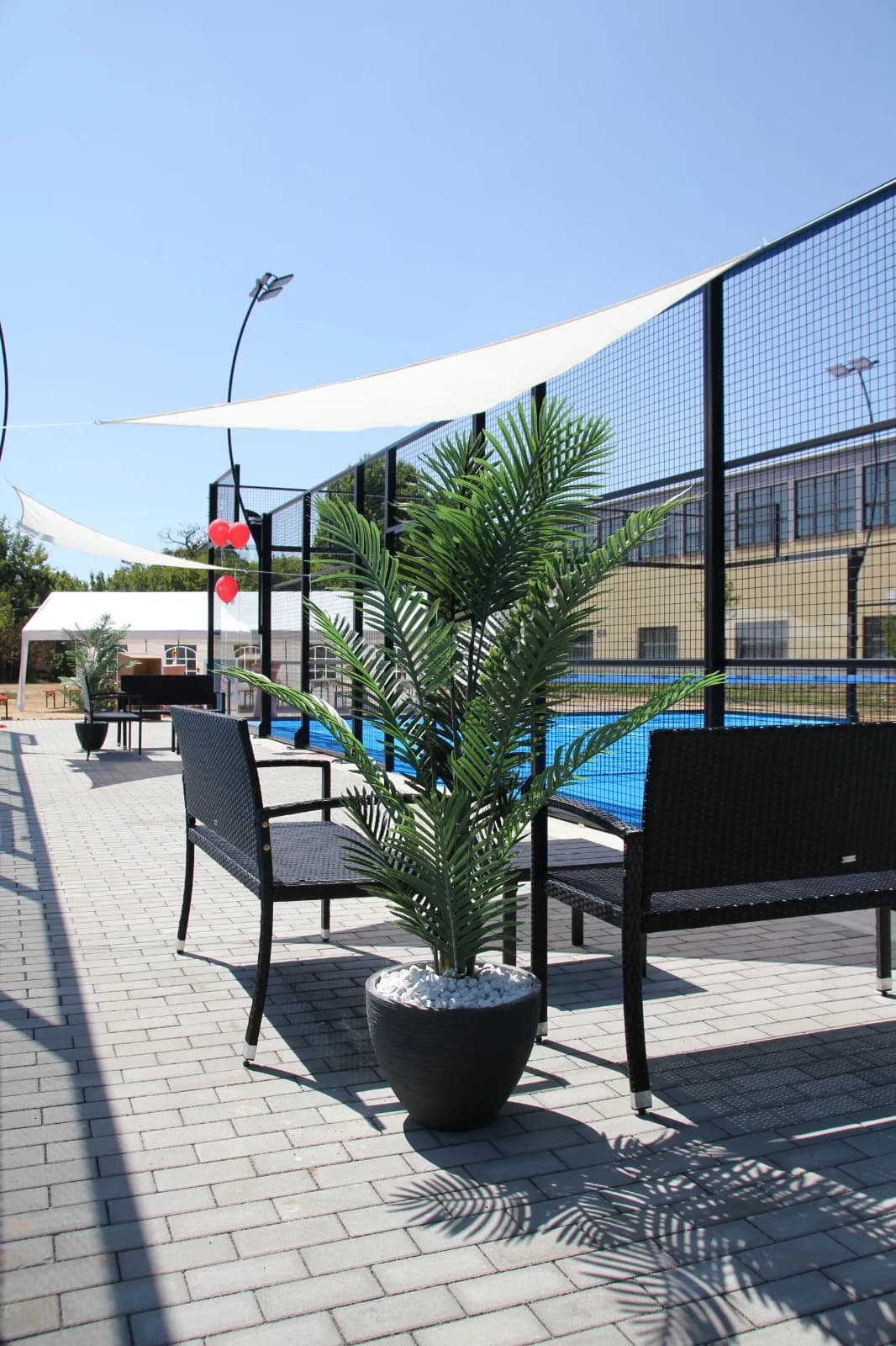 Lounge-Bereich mit Sitzmöbeln und Sonnensegeln neben dem Padelplatz