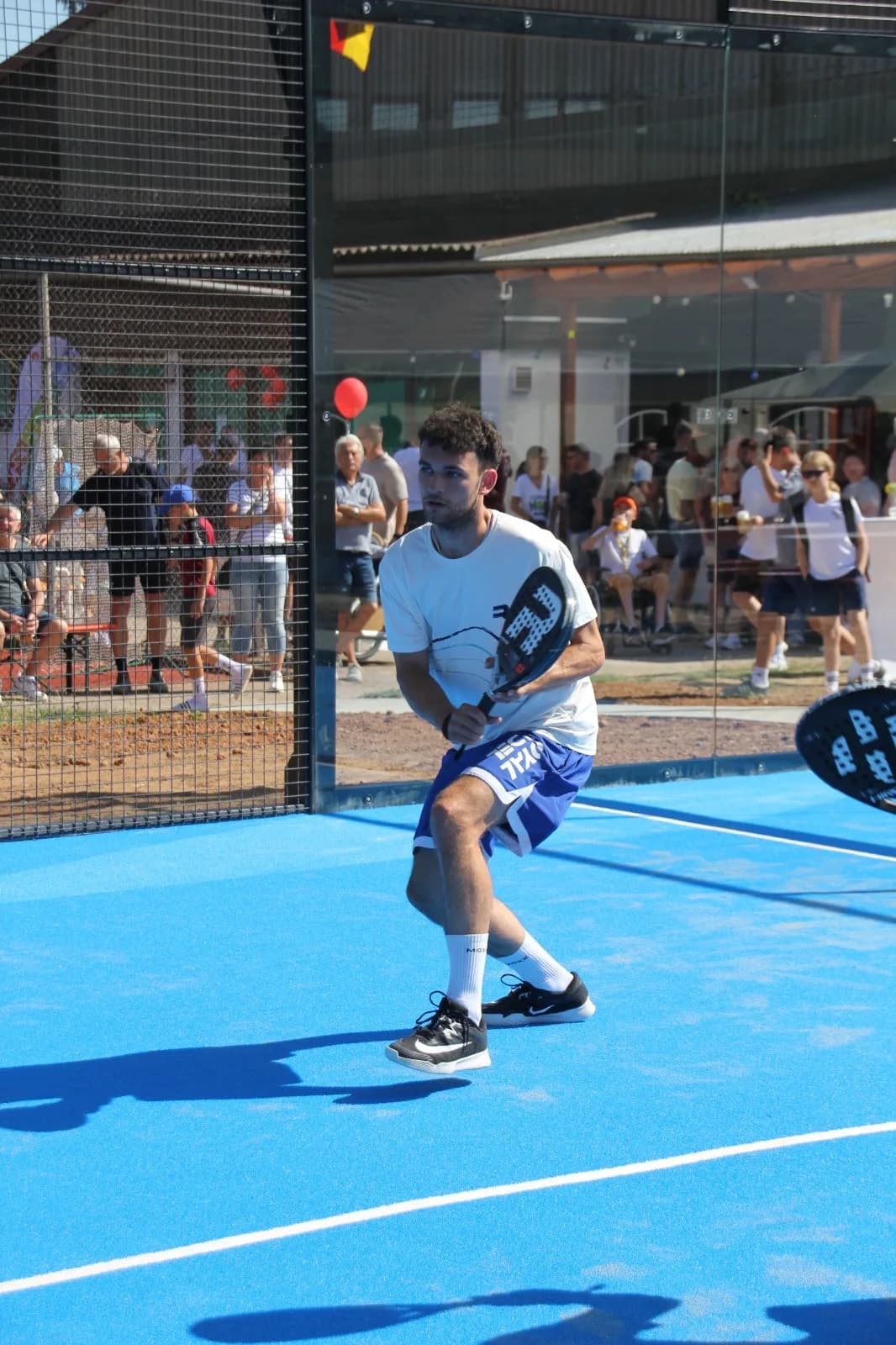 Padel-Profi in Rückhandposition vor den Zuschauern am Court
