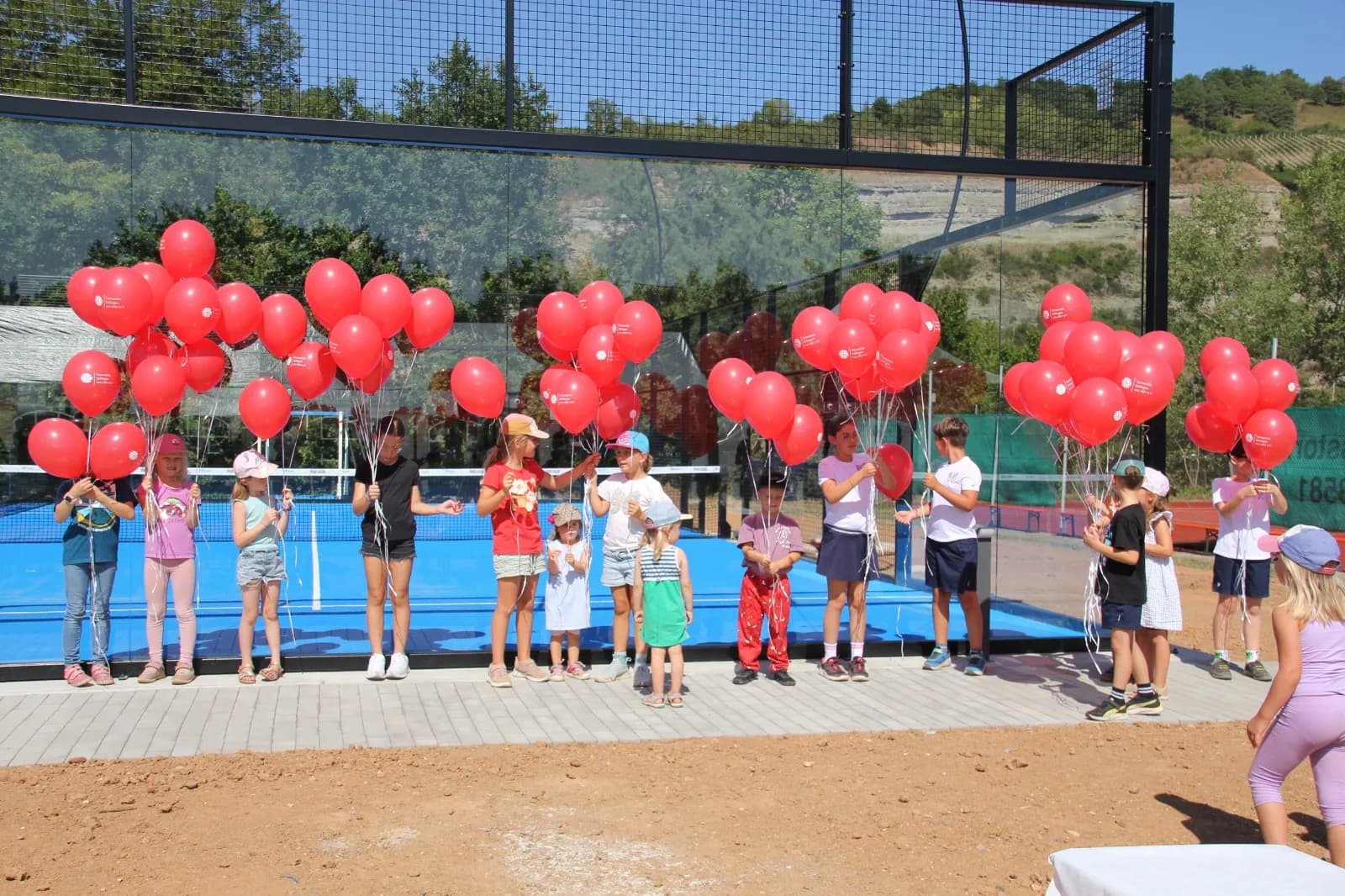 Kinder lassen rote Luftballons zur Eröffnung der Padelarena steigen